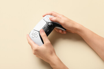 Gaming and entertainment, person holding modern wireless game controller for video games on beige background, leisure activity and digital hobby © Pixel-Shot