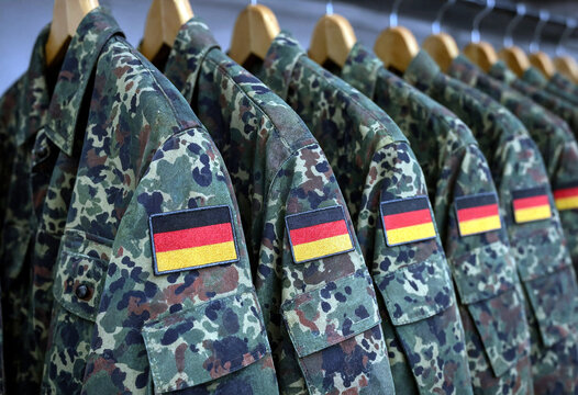 Row of german military camouflage uniforms with national flags on display in a store