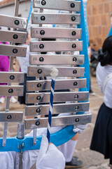 Child musician in marching band uniform plays glockenspiel with mallet and white gloves, striking metal bars during a lively street parade performance, focused and rhythmic © VICTOR A ARGUELLO