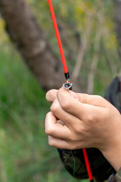 Vertical close-up of hands threading line through fishing rod tip guide