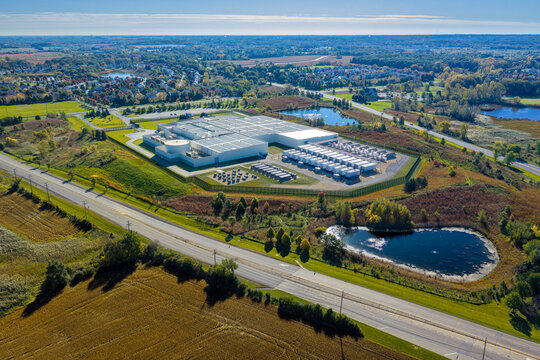 Aerial view of data center facility with solar panels on the roof, surrounded by green colorful fields and ponds,
autumn colors