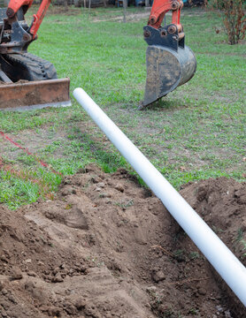 Heavy excavator digs trench for drainage pipe at Construccion site during excavation work.
