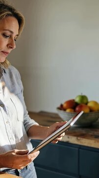 Vertical video: UI prompt urging woman in button-up tilting tablet in kitchen fruit bowl