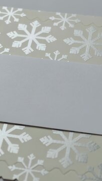 Vertical video: Sliding white strip tilting on table after nudge, revealing silver snowflake wrap