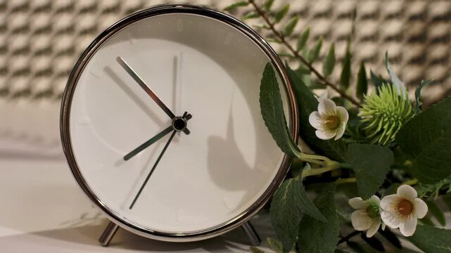 Modern Silver Table Clock with White Face and Fresh Flowers on Shelf