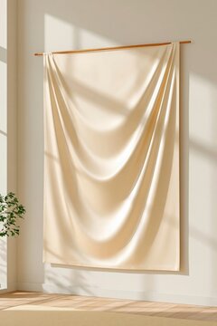 Cream silk fabric draped on wooden rod against white wall with natural sunlight casting soft shadows and green plant in corner