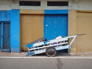 A cart is stopped at the side of the road in front of a warehouse building during the morning weather. © Arman