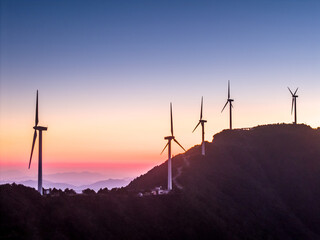 Obraz premium Wind turbines standing on mountain ridge at sunset