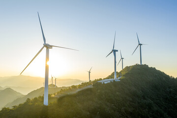 Fototapeta premium Wind turbines on mountain ridge at sunrise