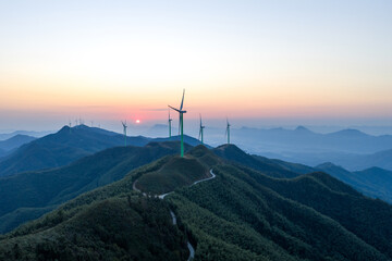 Obraz premium Wind turbines on green mountain peaks at sunset
