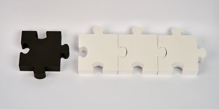 Black puzzle piece separated from three white pieces