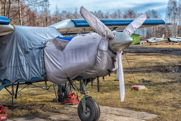 Light Aircraft with Protective Covers on Engine and Propeller Parked at Small Airfield © Evdoha