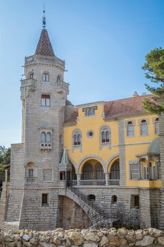 Exterior view of the historic Museu Condes de Castro Guimaraes castle with its stone tower and yellow facade in Cascais, Portugal.
