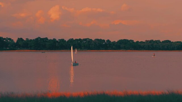 People enjoying watersports with sailboats and SUP boards in golden teal tone