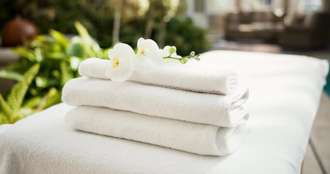 Towel, spa or massage bed in luxury resort with flowers for interior decor, physiotherapy or healing. Empty, fabric or cloth by swimming pool for zen, relaxation or stress relief in holiday retreat