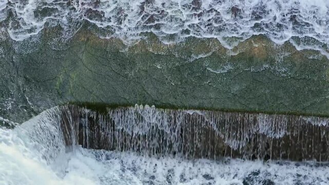 Detail shot of foaming white water rushing over the concrete steps of the Lechfall weir in Fussen, creating textured curtains of falling water on the Lech River.
