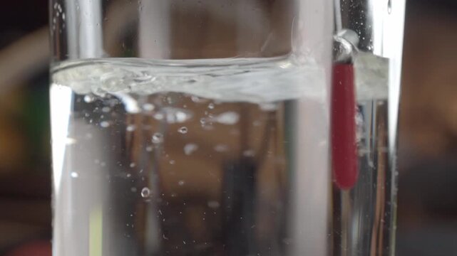 Close up of water bubbles created by stirring with a stick inside a clear glass container showing swirling liquid and fine bubbles suspended in water.