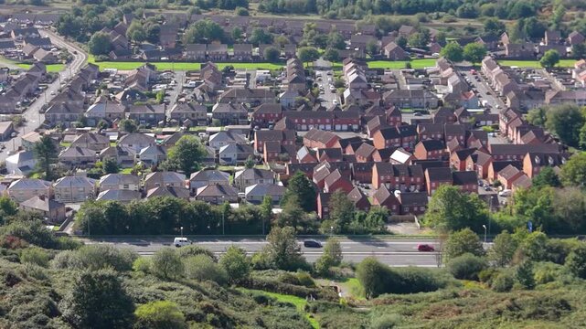 Rows of Houses near Busy Motorway with Natural Landscape in Foreground.