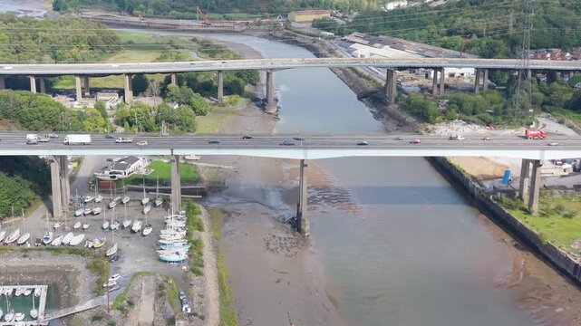 Aerial View of Busy M4 Motorway Overpass on River Neath with Docked Boats and Industrial Buildings Below.