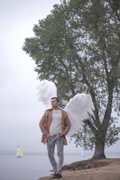 Angel man standing on lake shore near big tree with copy space