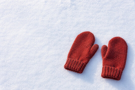 Pair of knitted mittens resting on snow with copy space