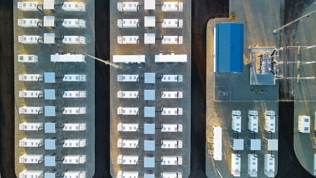 Modern battery energy storage park with rows of containerized BESS units, management building and electrical infrastructure at twilight, highlighting clean grid innovation and scale