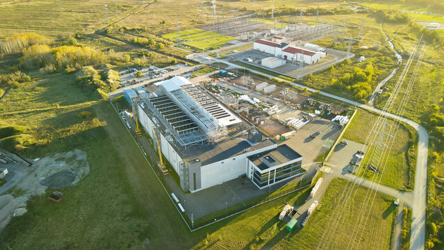 Modern data center campus under expansion with cranes, rooftop cooling units and nearby electrical substation at sunset, symbolizing global digital transformation and infrastructure advancement