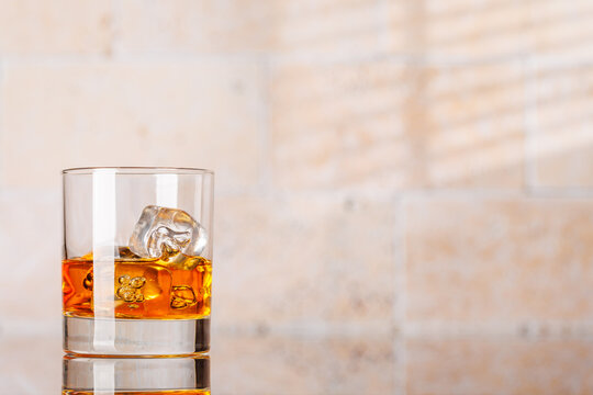 Whiskey with ice cubes against stone wall