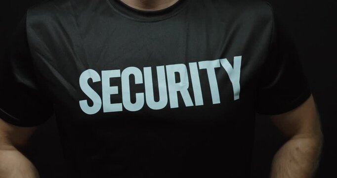 Close-up of a security guard wiping and adjusting his security shirt with both hands. Concept for security work, uniform preparation, professional service and protection.