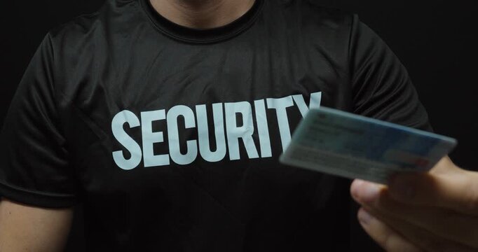 Close-up of a security guard checking an identification card. Concept for identity verification, access control, security checks and restricted entry.