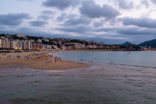 Tourists at Concha Beach at sunset