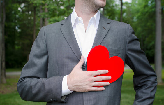 Mid section of man with red paper heart in hand