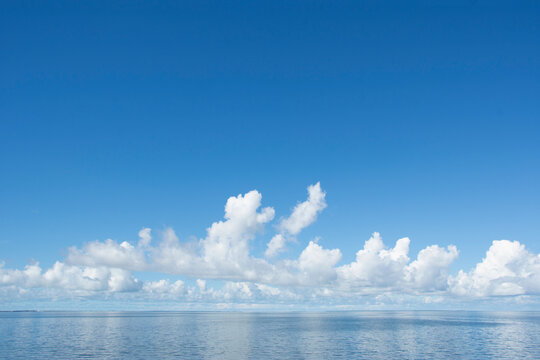 White puffy clouds over calm sea