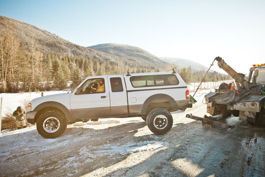Pickup truck getting towed on a snowy mountain road