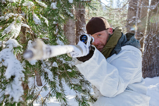 Portrait of a hunter aiming his rifel while hunter in winter