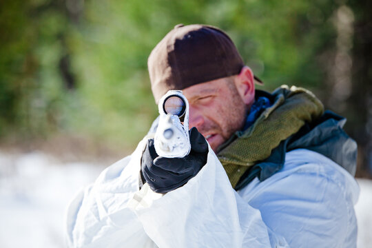 Man in winter camouflage aiming a rifle at the camera