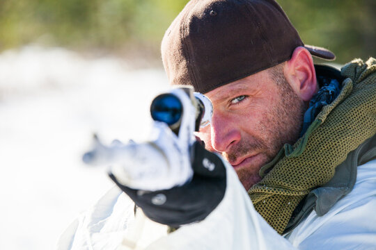 Man in winter camouflage aiming a sniper rifle