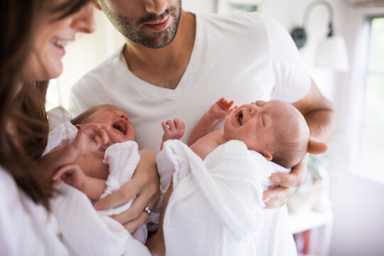 Mother and Father hold their twin babies, both screaming