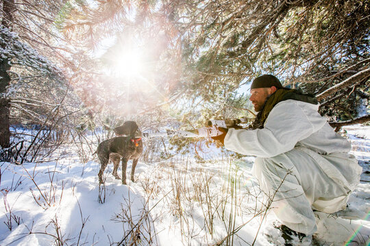 Hunter and his dog search for prey in a snowy forest