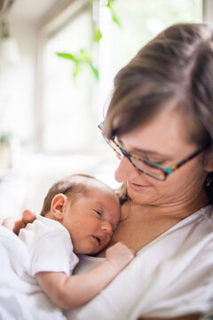 Woman tenderly holding her sleeping newborn baby