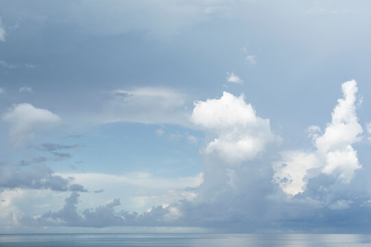White puffy clouds over calm sea at morning