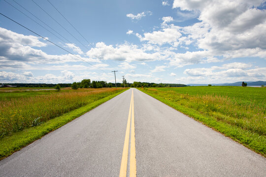 Empty rural road crossing grassy fields