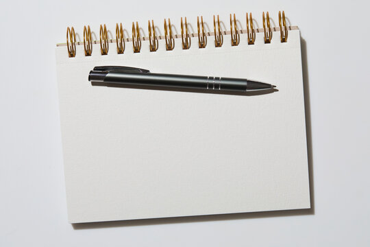 Blank notebook and pen on white background