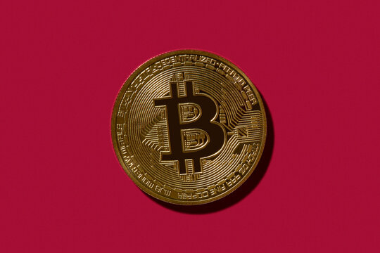 Golden Bitcoin on red background