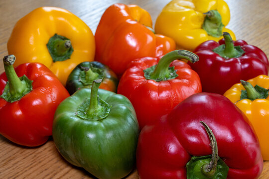 Red, yellow, orange, and green bell peppers on a table.