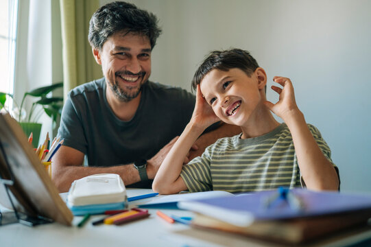 Smiling father helping his son with homework at home