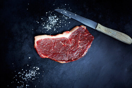 Raw striploin steak, salt and knife