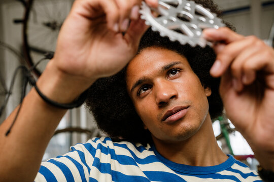 Urban bike enthusiast repairing gear indoors with focus and smile