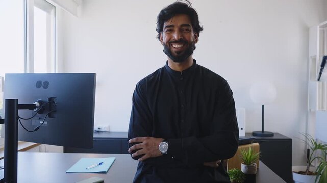 Pakistani Business man in the office. Corporate scene in a modern office with a businessman from pakistan in traditional jubba kandora.