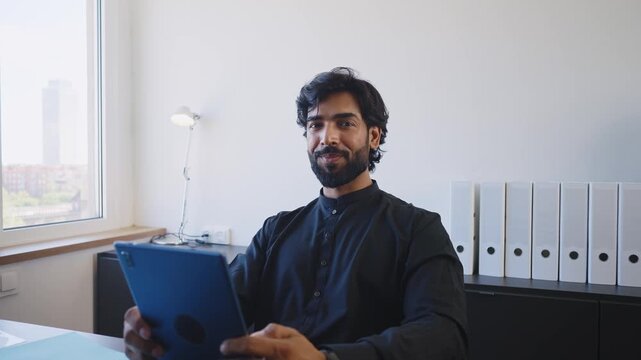 Pakistani Business man in the office. Corporate scene in a modern office with a businessman from pakistan in traditional jubba kandora.